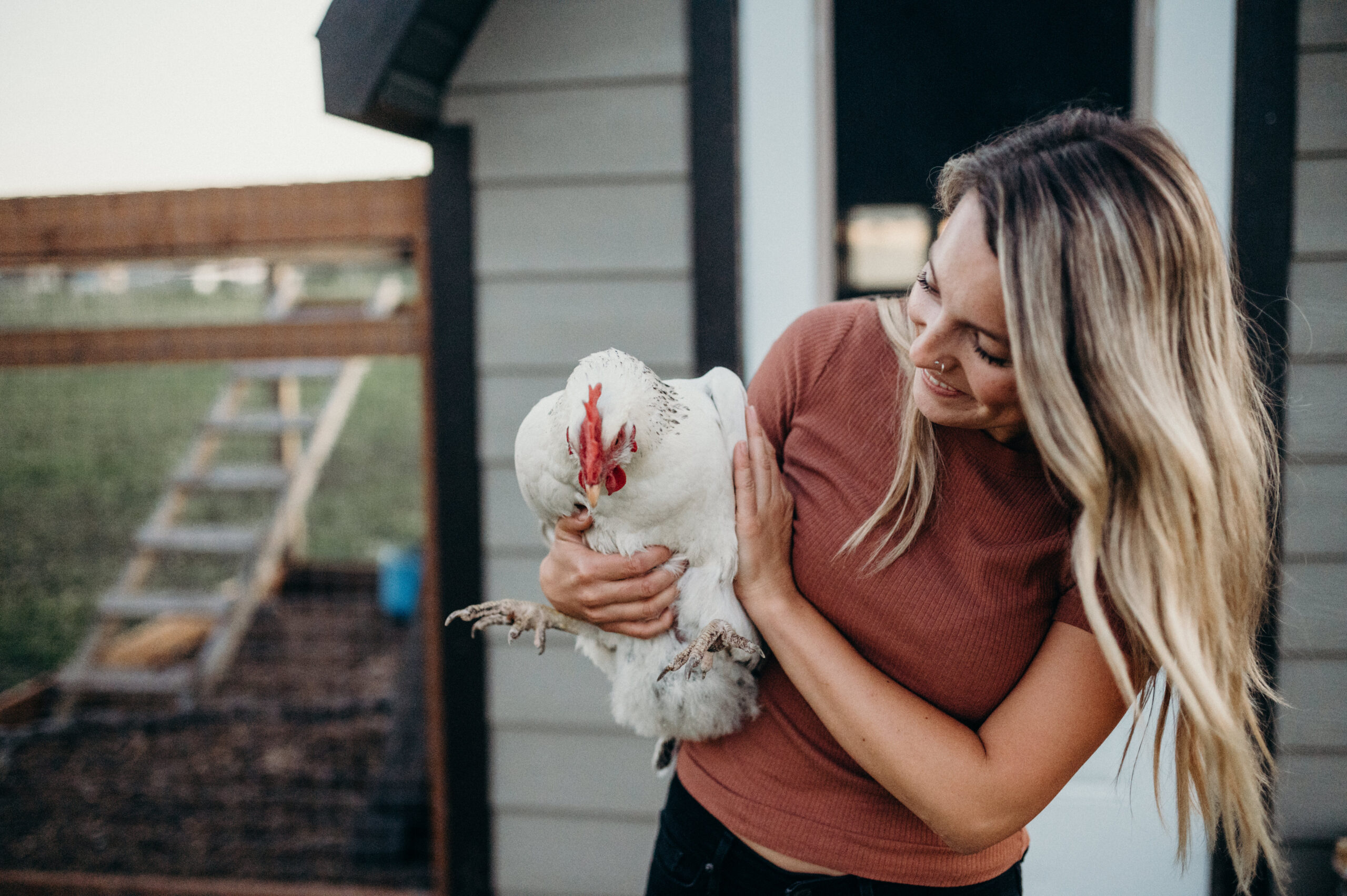 Maggie Wysocki holding her chicken with the coop behind