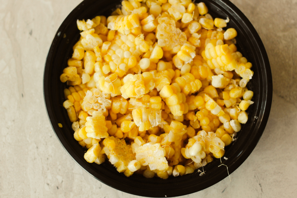 Corn kernels in a black circular container on a white granite countertop