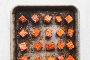 Cubes of marinated tempeh on a baking sheet