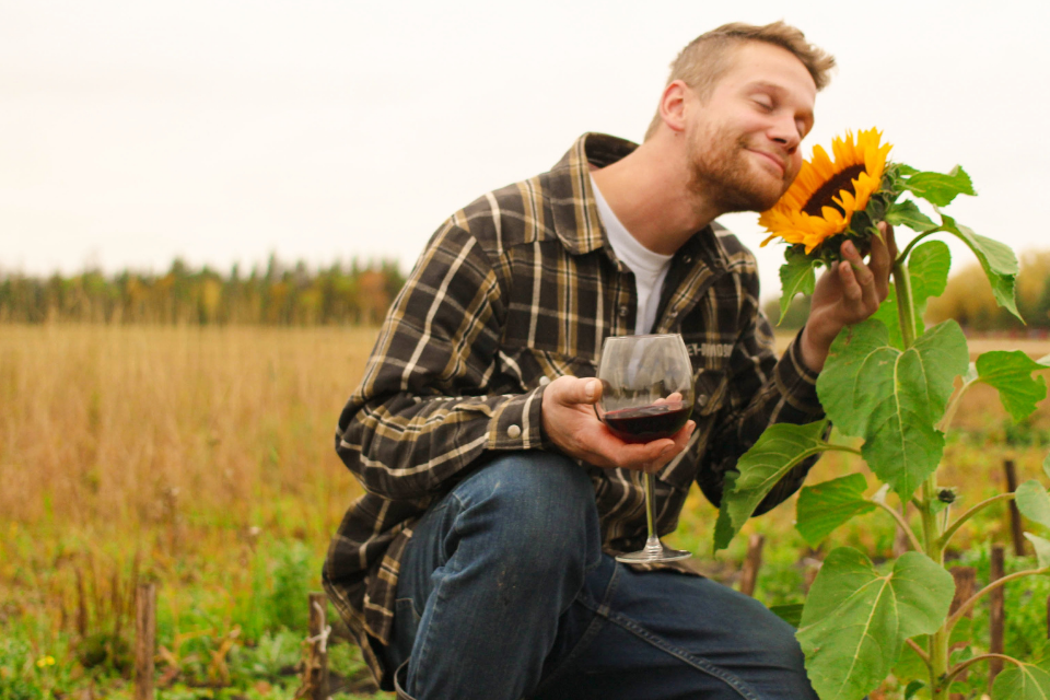 Maggie's husband Justin with sunflower in one hand and glass of red wine in the other