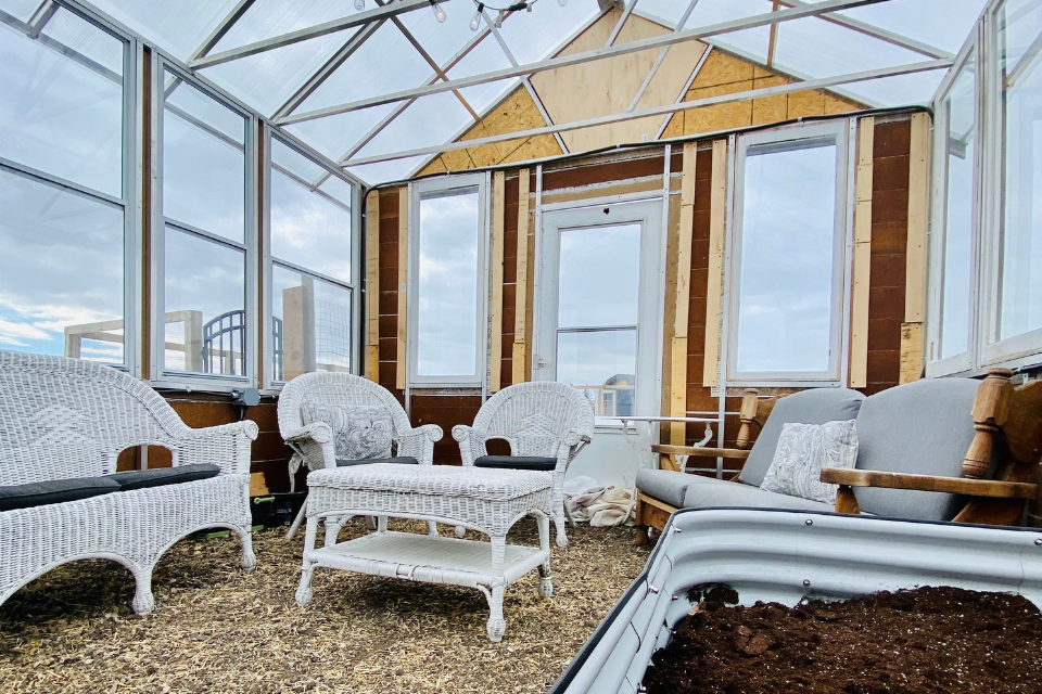 Interior shot of zone 3 greenhouse with furniture and raised bed