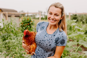 Woman holding chicken in garden