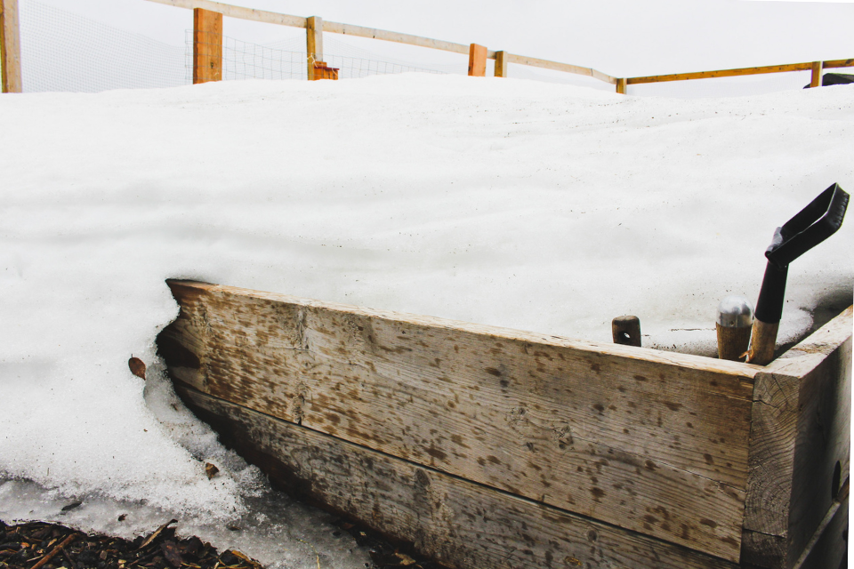 Wooden raised bed garden covered in snow